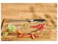 Fusil à aiguiser avec poireaux, carottes et piments coupés sur une planche en bois.