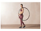Une femme en tenue de sport tient un cerceau de fitness.