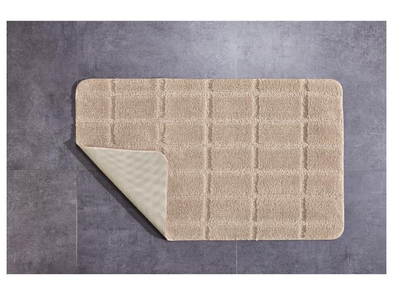 Tapis de bain beige à carreaux sur un sol en carrelage gris