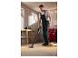 Homme aspirant de la sciure avec un aspirateur sans fil dans un atelier.