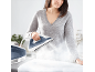 Une femme utilisant une centrale vapeur pour repasser un tissu blanc sur une table à repasser.