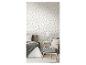 Chambre à coucher avec papier peint floral, lit avec literie grise et fauteuil pied-de-poule.