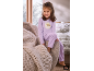 Fille en pyjama violet avec ourson, assise sur un fauteuil à côté d'une couverture tricotée.