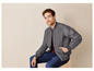 Un homme portant une veste bomber grise de Outdoor Life, un t-shirt rouge et un jean bleu.