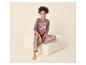 Femme en pyjama à motif floral et inscription « SLEEP WELL » assise sur un pouf.