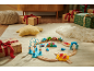 Train jouet en bois avec animaux marins sur un tapis, entouré de cadeaux.