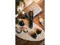 Tondeuse homme noire avec accessoires, huile et montre sur un plateau en marbre.