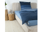 Chambre avec parure de lit rayée bleue, drap-housse bleu clair et deux tables d'appoint en bois.