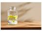 Distributeur de boissons en verre avec robinet, rempli d'eau, de tranches de citron vert et de glaçons.