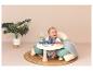 Un bébé assis dans une chaise gonflable avec une table de jeu.