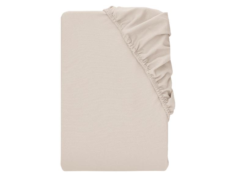 Drap-housse beige plié avec un bord élastique froncé.