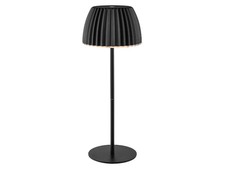 Lampadaire noir avec un abat-jour plissé, émettant une lueur chaude.