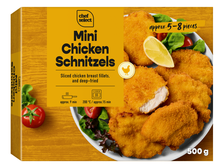 Boîte de mini-schnitzels de poulet avec une assiette de schnitzels cuits, citron et salade.