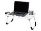 Table pliante blanche avec un ordinateur portable et une tasse grise.