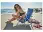Femme en maillot de bain noir et lunettes de soleil assise sur une chaise de plage bleue, appliquant de la crème solaire.