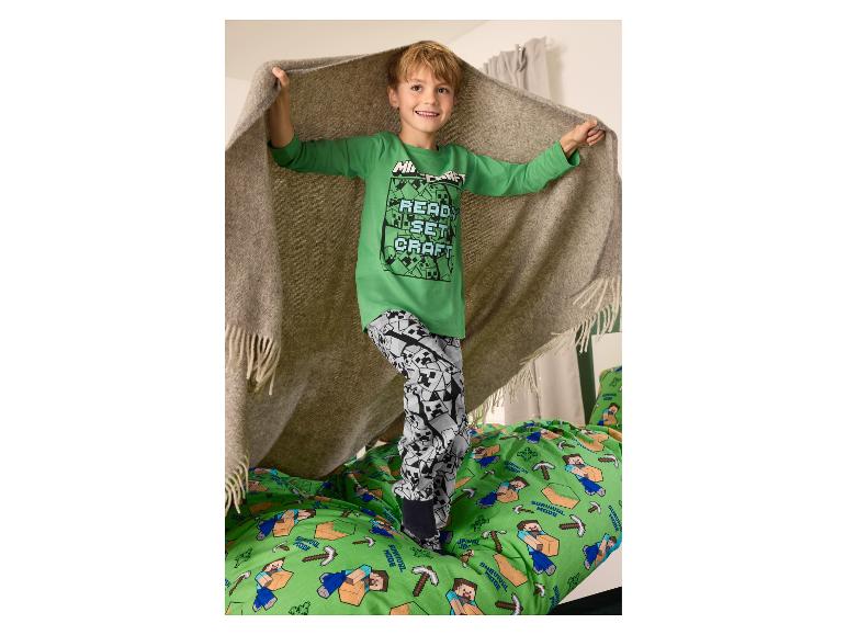 Garçon en pyjama Minecraft vert avec le texte 'READ, SET, CRAFT', debout sur une couette Minecraft.