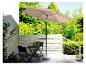 Un parasol beige avec une table et des chaises noires sur une terrasse.
