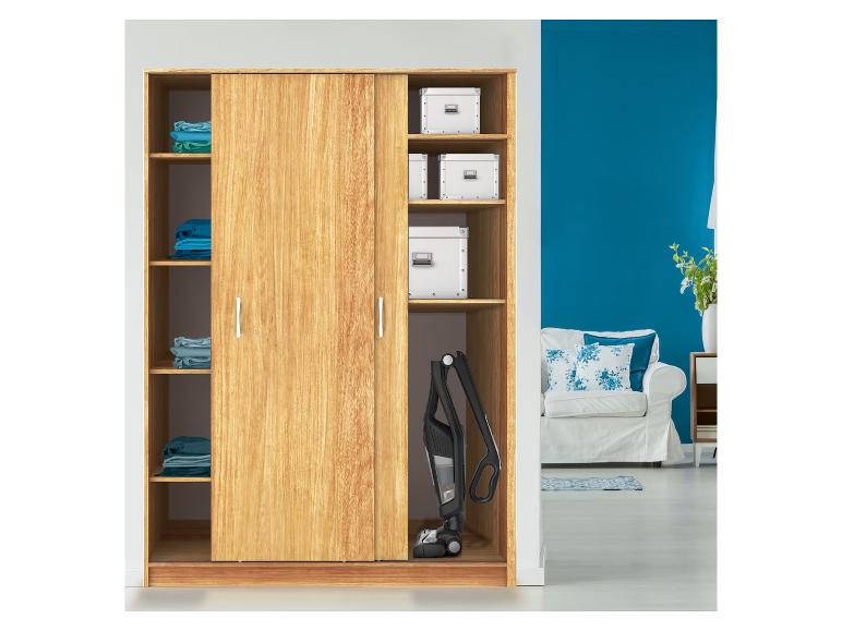 Armoire en bois avec portes coulissantes, vêtements pliés, boîtes de rangement et aspirateur balai.