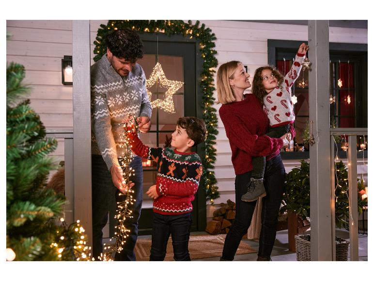 Famille décorant leur maison avec des lumières et décorations de Noël.