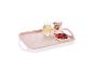 Plateau rectangulaire rose à pois blancs avec des fruits rouges, un verre et un vase.
