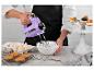 Une femme utilise un batteur sur socle violet pour battre de la crème pour des cupcakes