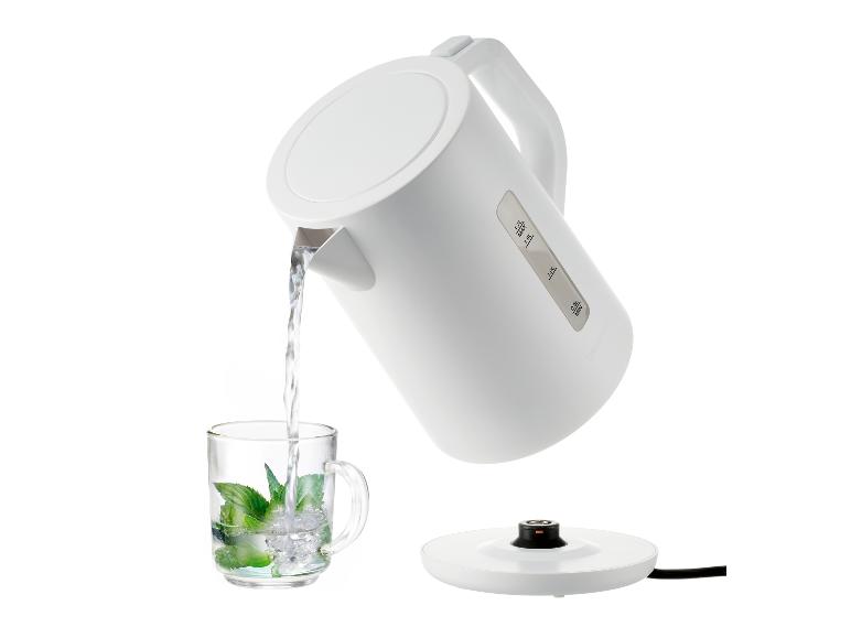 Bouilloire blanche versant de l'eau dans un verre avec de la menthe et de la glace.