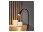 Une lampe de bureau noire avec pince, des crayons et un carnet sur un bureau en bois.