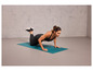 Une femme fait des pompes sur un tapis de yoga bleu.