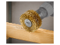 Une brosse métallique en laiton fixée à une perceuse polit un morceau de bois.