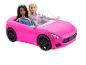 Deux poupées Barbie dans une voiture de sport rose.