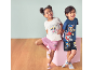 Deux enfants souriants en pyjamas d'été avec des imprimés de chiots, sur fond bleu clair et parquet.