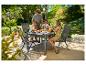 Famille prenant le petit-déjeuner à une table et des chaises de jardin en extérieur.