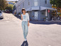 Femme en t-shirt blanc avec l'inscription 'Free Spirit' et un jean, marchant dans la rue.