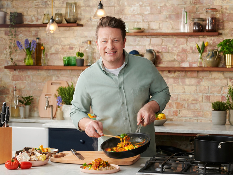 Un homme cuisine un curry dans une poêle dans la cuisine.