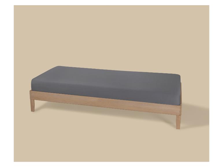 Banc en bois avec matelas gris sur fond beige.