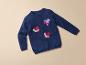 Un pull bleu avec trois cœurs en paillettes