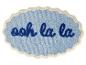 Tapis de bain bleu avec l'inscription 'ooh la la' en bleu foncé et bord ondulé.