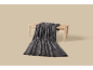 Couverture douce gris foncé nonchalamment posée sur un banc en bois.
