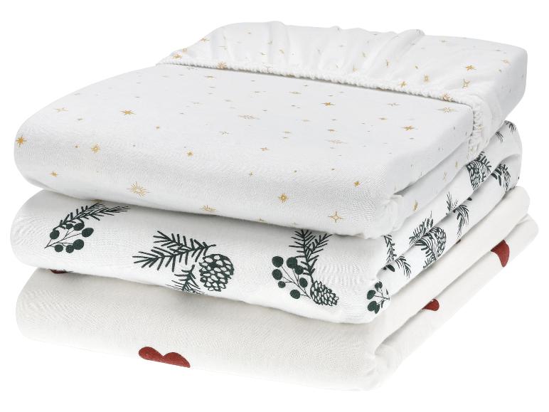 Trois ensembles de draps de bébé avec des motifs d'étoiles, de pommes de pin et de cœurs.