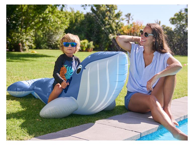 Enfant sur une bouée baleine gonflable près d'une piscine.