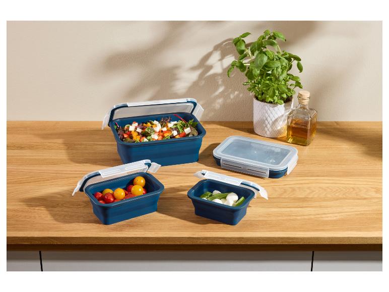 Ensemble de boîtes alimentaires pliables bleues avec salades et collations sur un comptoir en bois.