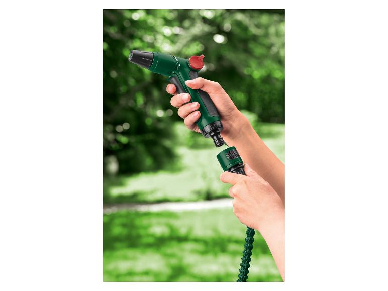 Mains connectant un tuyau d'arrosage vert à un pistolet pulvérisateur vert avec un bouton rouge.