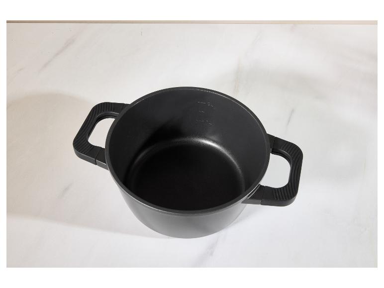 Casserole noire avec deux poignées et graduations sur une surface en marbre blanc