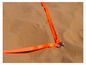 Un ruban orange avec un crochet en métal dans le sable.
