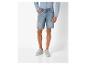 Un homme portant un short en jean bleu clair et des baskets blanches.