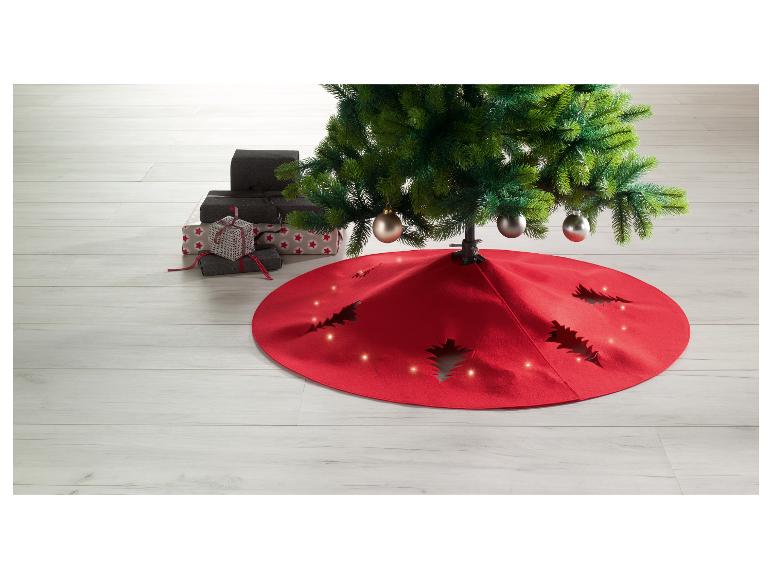 Jupe de sapin de Noël rouge avec lumières et cadeaux au sol.