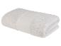Une serviette de bain blanche pliée sur un fond blanc.