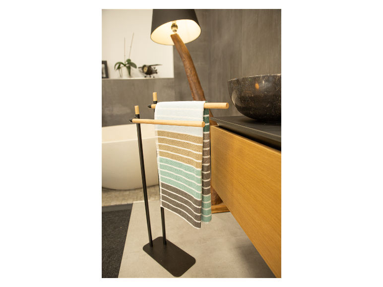 Séchoir à serviettes noir sur pied avec serviettes rayées dans une salle de bain moderne.
