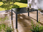 Une table en métal noir avec un plateau en verre pour l'extérieur.