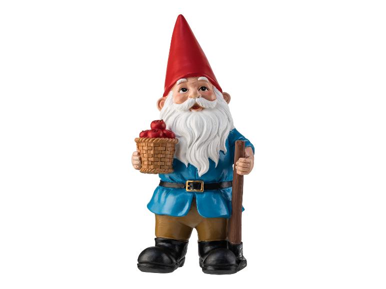 Un gnome de jardin avec un panier plein de pommes et une pelle.